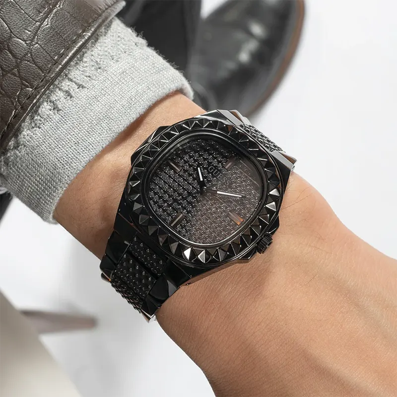 Guess Rebel watch worn on wrist showing black pyramid-studded case and bracelet